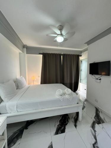 a white bed in a room with a ceiling fan at Las Palmeras by Graziano in Boca Chica