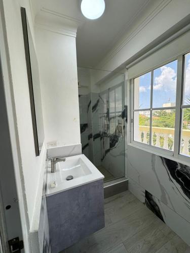 a white bathroom with a sink and a window at Las Palmeras by Graziano in Boca Chica