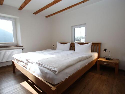 a large bed in a room with two windows at Eifeler farmhouse in Plütscheid