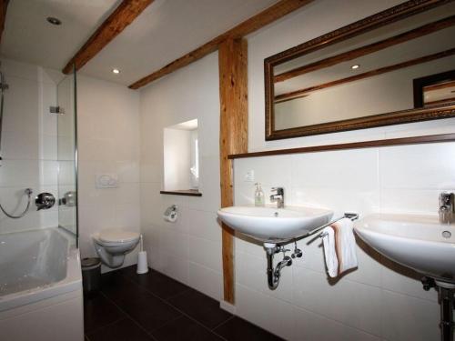 a bathroom with two sinks and a toilet and a mirror at Eifeler farmhouse in Plütscheid