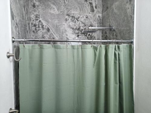 y baño con ducha con cortina verde. en Departamento cerca de la Universidad de Montemorelos en Montemorelos