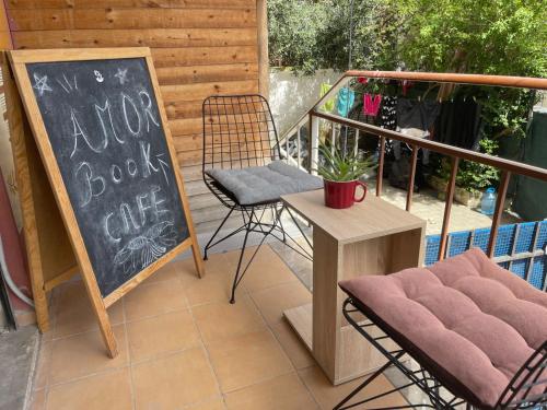 a patio with a table and a chair and a chalkboard at Amor_Bookstore in Durrës