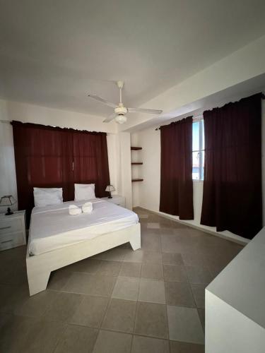 a bedroom with a white bed and a ceiling fan at Las Palmeras by Graziano in Boca Chica