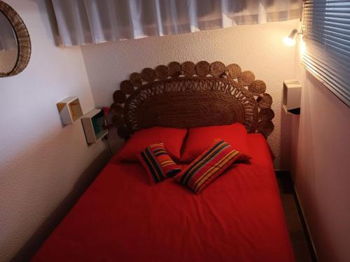une chambre avec un lit rouge avec deux oreillers dans l'établissement Appartement lumineux à Agde avec vue sur la mer - 34 m², au Cap d'Agde