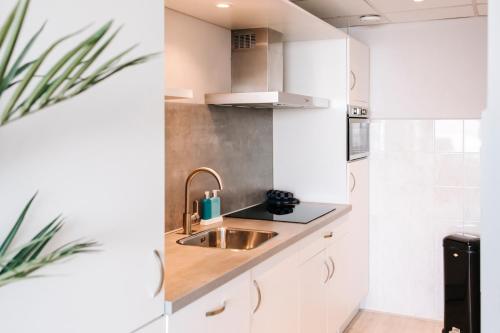 eine Küche mit weißen Schränken und einem Waschbecken in der Unterkunft Studio Maxime in Zandvoort