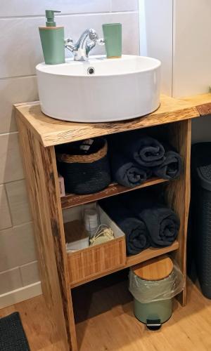 La salle de bains est pourvue d'un lavabo en bois et de serviettes. dans l'établissement Appartement l'Embarcadère, à Boulogne-sur-Mer