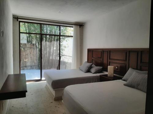 sypialnia z 2 łóżkami i dużym oknem w obiekcie Cuernavaca Eden Hotel Boutique doble w mieście Cuernavaca