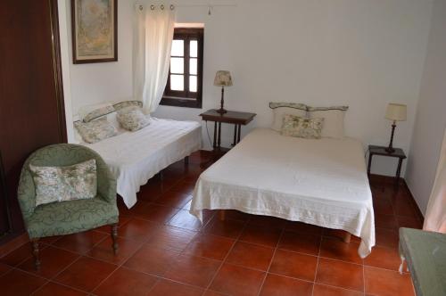 a room with two beds and a chair and a window at Sunday every Day in Olho Marinho