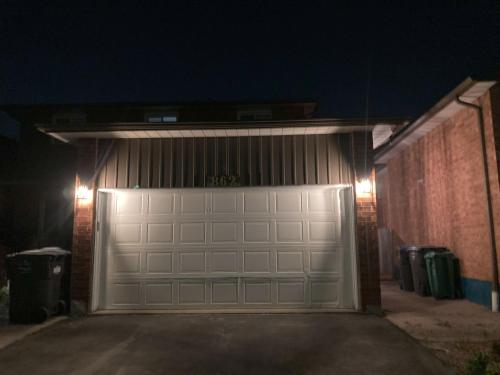 a garage with a white garage door at night at Brand New, cozy 2 Bdrm Bsmnt Apt in Mississauga
