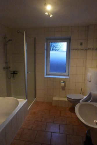 een badkamer met een bad, een toilet en een raam bij Großzügige Wohnung auf Resthof in Jevenstedt
