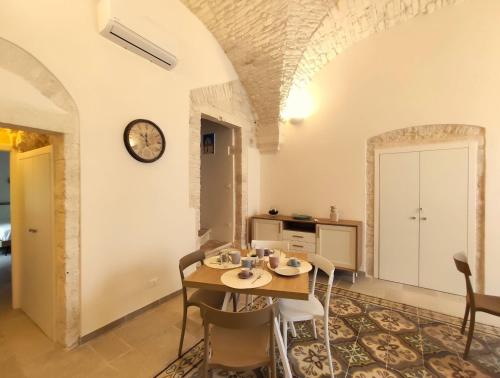 a dining room with a table and a clock on the wall at Palazzo d'Itria - Luxury holiday in Valle d'Itria in Martina Franca