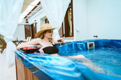 kobieta siedząca w basenie z kieliszkiem wina w obiekcie Erotokritos Deluxe Suite With Jacuzzi w mieście Perivólia