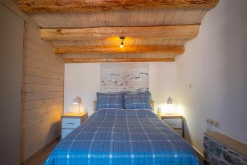 a bedroom with a blue bed with two night stands at A window to the Aegean in Kokkari