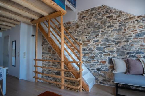 a wooden staircase in a room with a stone wall at Anxhelo Apartment in Kokkari