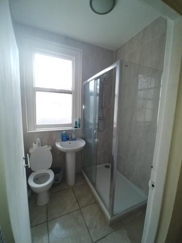 a bathroom with a toilet and a shower and a sink at Sussex Lodge Guest House in Slough