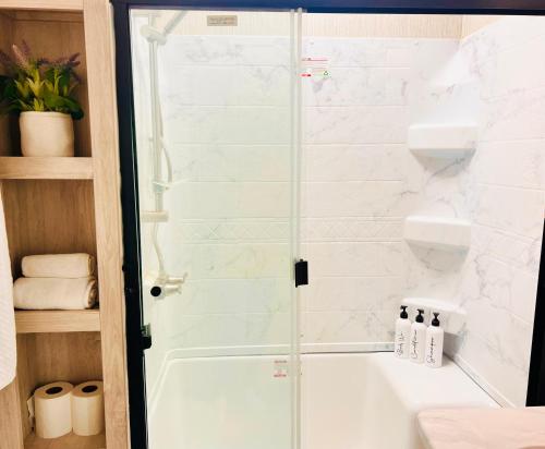 a shower with a glass door in a bathroom at Breezes Park in Acton