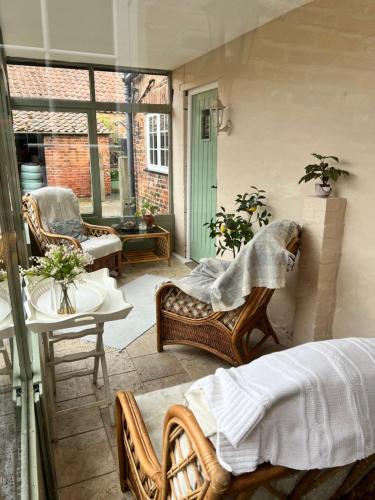 - une terrasse couverte avec un lit, une table et des chaises dans l'établissement Beech cottage ~ close to York ~ cozy rural stay, à Stamford Bridge
