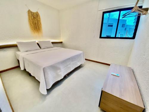 Schlafzimmer mit einem Bett, einem Tisch und einem Fenster in der Unterkunft Villas Manatee Milagres C006 in Pôrto de Pedras