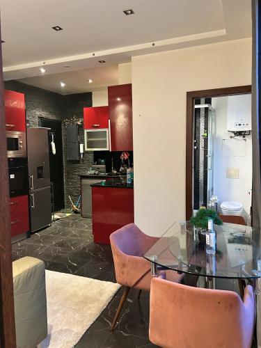 une cuisine avec une table en verre et des armoires rouges dans l'établissement Appartement Loft Lumière T2 à Ivry-sur-Seine, à Ivry-sur-Seine