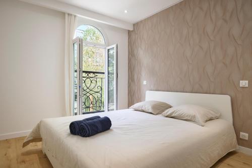 une chambre avec un grand lit blanc avec une fenêtre dans l'établissement VILLA DES PERGOLAS au pied du TRAM ,à 5 min des plages , 15 min du Centre , jacuzzi, à Nice