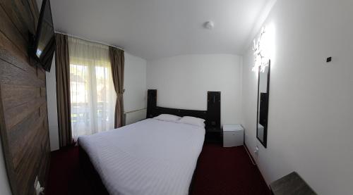 a bedroom with a white bed and a window at Pensiunea Miruna in Moieciu de Jos