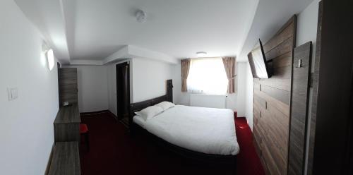 a bedroom with a white bed and a window at Pensiunea Miruna in Moieciu de Jos
