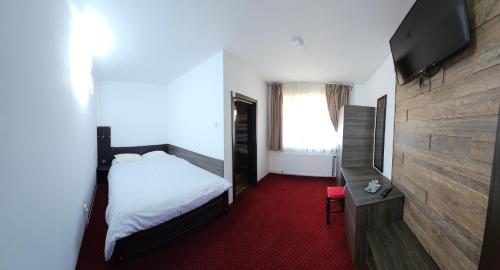 a bedroom with a bed and a flat screen tv at Pensiunea Miruna in Moieciu de Jos
