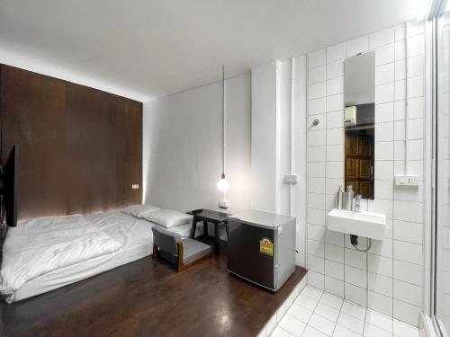 um quarto com uma cama e uma casa de banho com um lavatório em Chatel BKK em Bang Rak