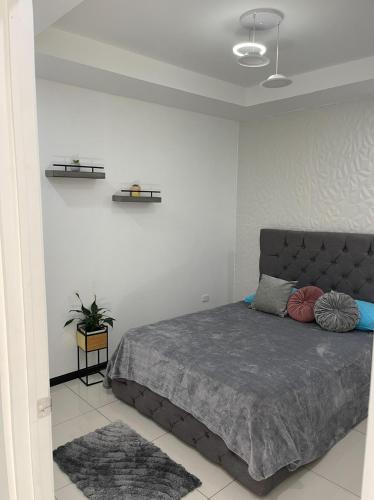 ein Schlafzimmer mit einem Bett in einem weißen Zimmer in der Unterkunft 5 min Aeropuerto in Alajuela