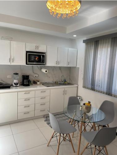 eine Küche mit weißen Schränken, einem Glastisch und Stühlen in der Unterkunft 5 min Aeropuerto in Alajuela