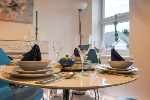 a table with plates and wine glasses on it at The Sashes - Stylish Apartment - FREE Parking - Ultrafast WIFI - Smart TV - Netflix - sleeps up to 6! Close to Poole Town Center & Sandbanks & Bournemouth in Poole