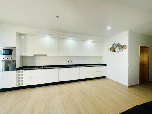 a large kitchen with white cabinets and a wooden floor at Aparthotel Di lia t3 in Praia