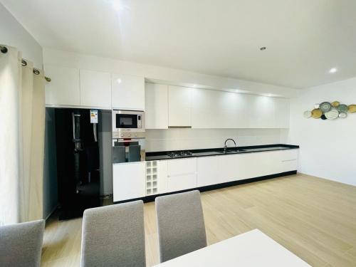 a kitchen with white cabinets and a black refrigerator at Aparthotel Di lia t3 in Praia