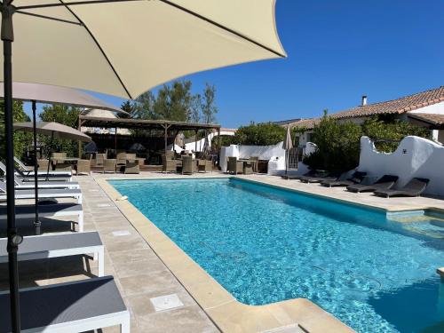 une piscine avec des chaises et un parasol dans l'établissement Mas Des Salicornes, à Saintes-Maries-de-la-Mer