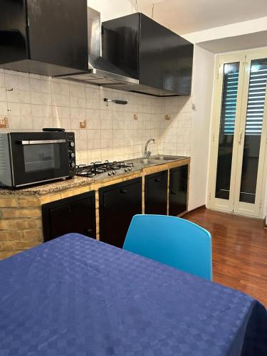 een keuken met een tafel met blauwe stoelen en een magnetron bij Casa Vacanze VicoX in Lanciano