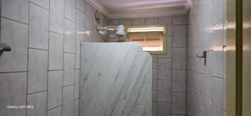 a bathroom with a shower with a sink and a window at Apartamento Guriri Verão in São Mateus