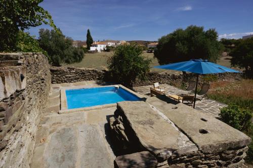 a blue swimming pool with an umbrella and a bench at Casa dos Primos in Muxagata