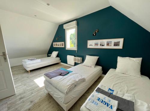 1 dormitorio con 2 camas y pared azul en Les Palmiers gite 7 personnes plages du débarquement, en Grandcamp-Maisy