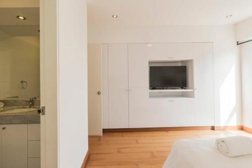 a white kitchen with a television on the wall at Stylish 2BR at Malecon in Lima