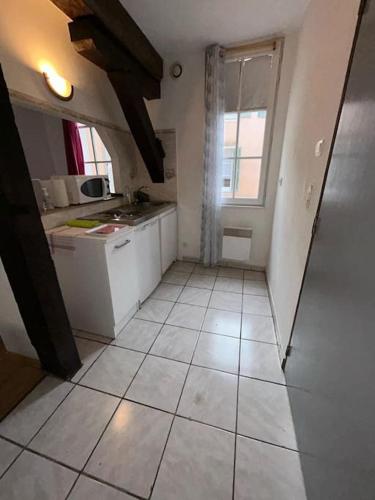 Il comprend une cuisine dotée de carrelage blanc et d'une fenêtre. dans l'établissement Appartement La Clouterie, à Chartres