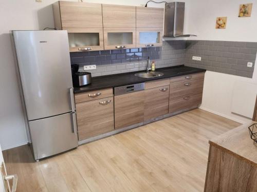 a kitchen with a stainless steel refrigerator and wooden cabinets at Ferienhaus Lichtenberg 15 in Herleshausen