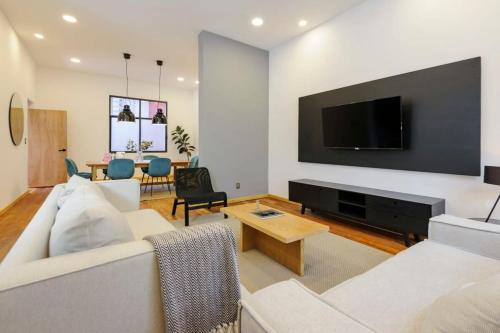 sala de estar con sofá blanco y TV de pantalla plana en Perfect 3BR Duplex in Cuauhtemoc, en Ciudad de México