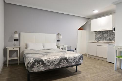 a white bedroom with a bed and a kitchen at Apartamentos La Cueva - Onis in Avín