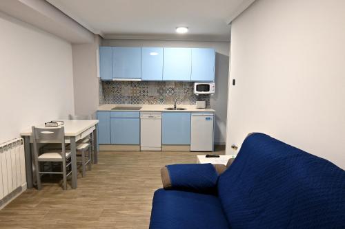 a kitchen with blue cabinets and a blue couch at Apartamentos La Cueva - Onis in Avín