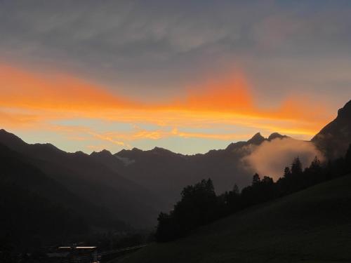 a sunset over a mountain range with clouds in the sky at Apartment Weisswand in Colle Isarco
