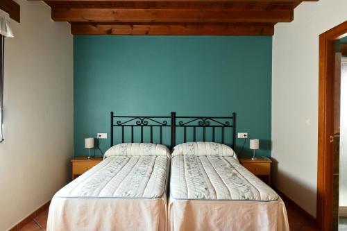 1 cama en un dormitorio con una pared azul en Apartamentos Aires De Avin - Onis, en Avín