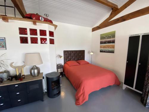 um quarto com uma cama com um cobertor vermelho em Le Loft em Port-Sainte-Foy-et-Ponchapt