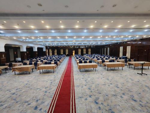 un gran salón de banquetes con sillas y alfombra roja en Almansour Hotel en Bagdad