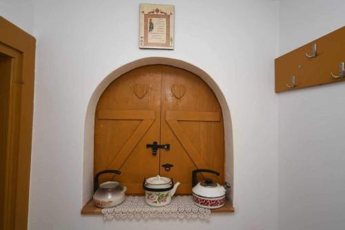 a door in a wall with two pots on a shelf at Salaš Trikić in Aleksandrovo