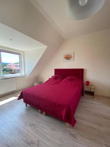 1 dormitorio con 1 cama grande con colcha roja en Słoneczne Apartamenty Polanica-Zdrój en Polanica-Zdrój